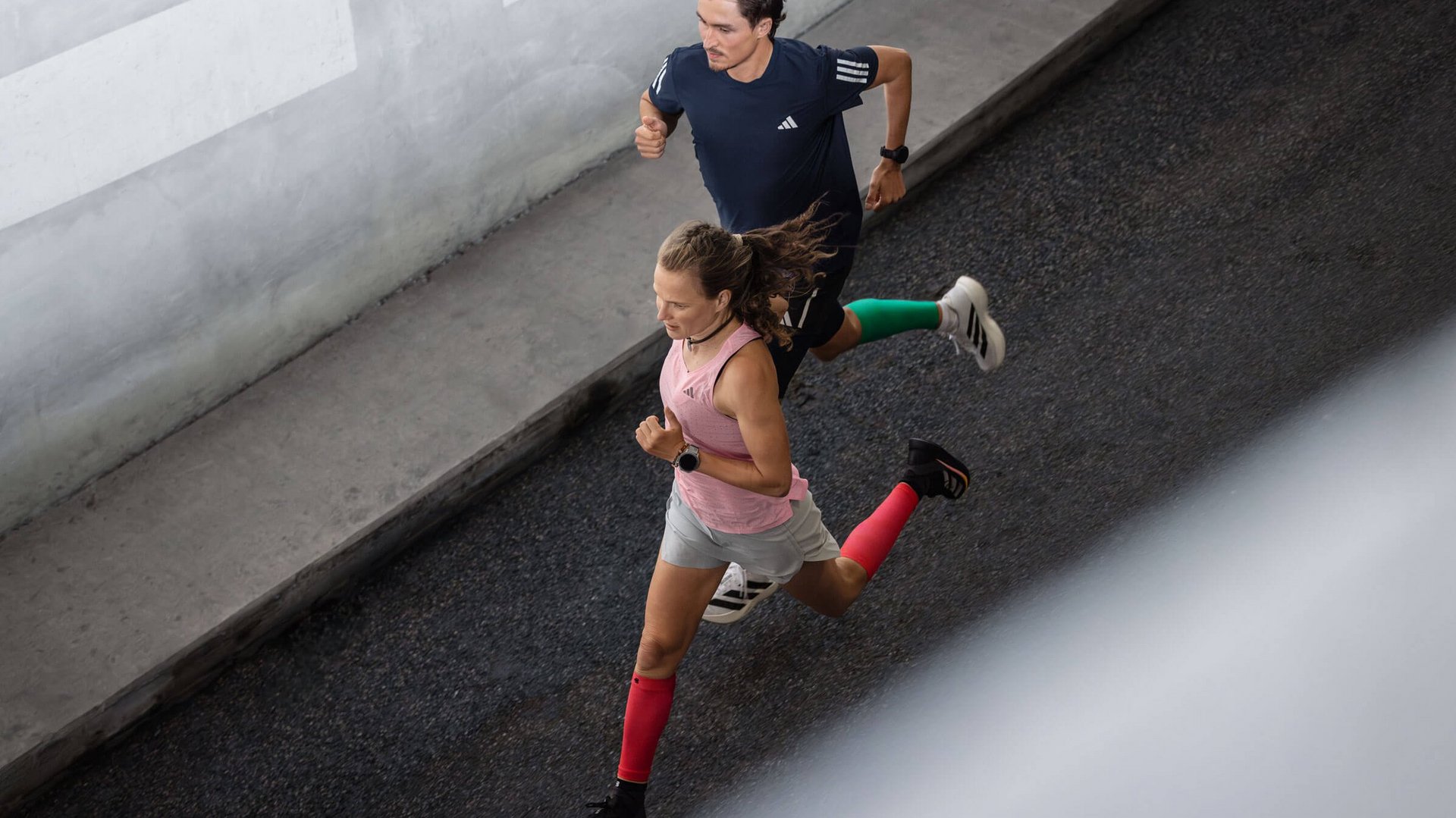 Zwei Läufer mit Compression Sleeves von Bauerfeind laufen eine Strasse herunter.