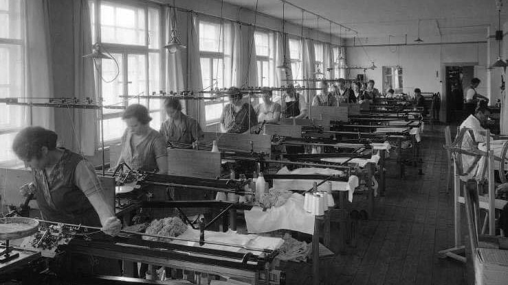 Historisches Schwarz-Weiß-Foto, aufgenommen im Jahr 1929 in Zeulenroda. Er steht vor einer Gummistrickerei, dem ersten Produktionsstandort des Unternehmens, das sich auf medizinische Kompressionsstrümpfe spezialisierte.