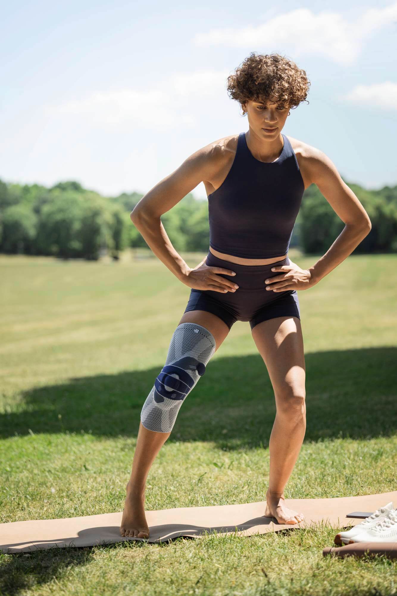 Eine Frau im Park macht Bewegungsübungen mit Kniebadage.