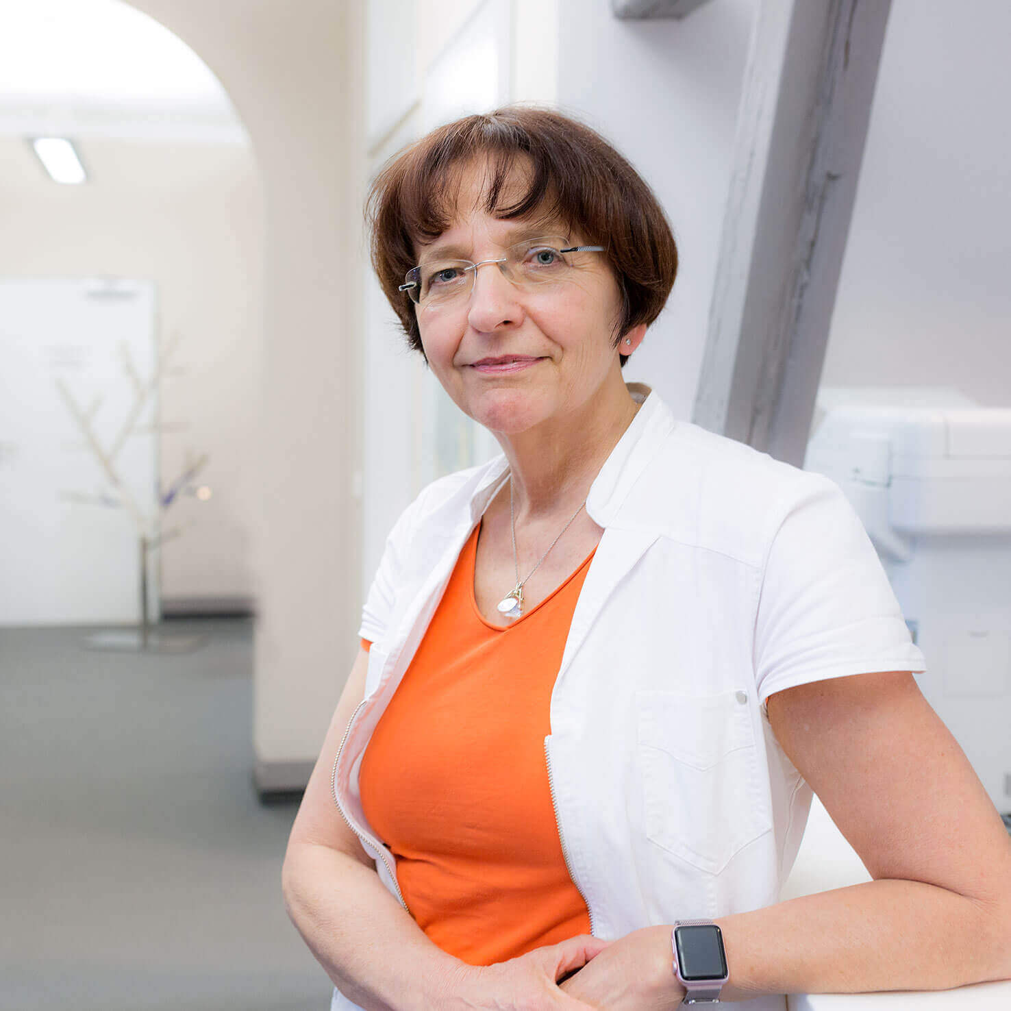 Dr. med. Christine Zollmann, Fachärtzin für Dermatologie und Venerologie steht im Krankenhausflur und lächelt freundlich in die Kamera.